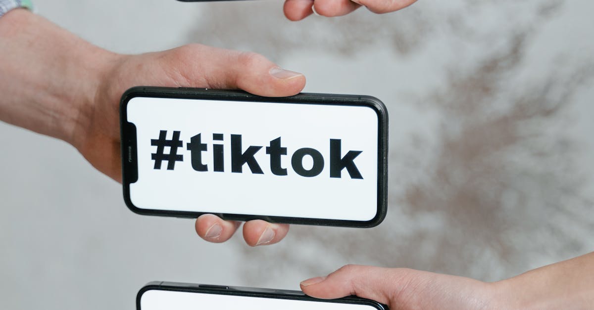 Hands holding smartphones displaying TikTok hashtag, emphasizing social media connection.